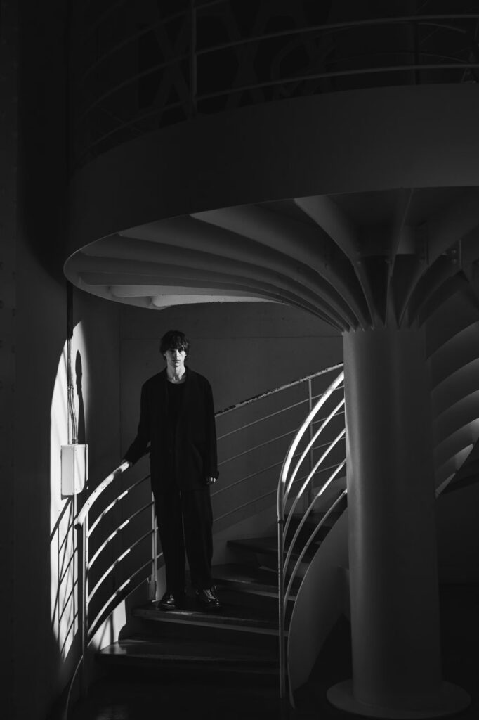 螺旋階段に立つYohji Yamamoto POUR HOMME × WESCOのルック